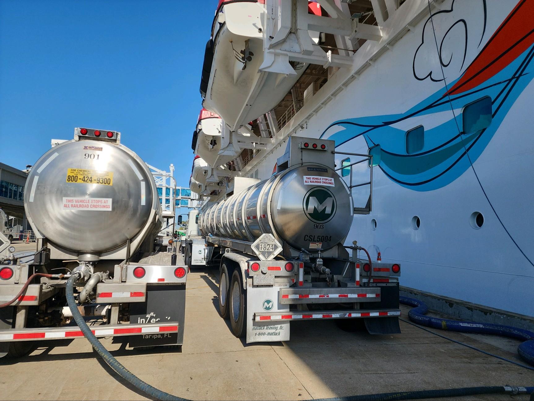 Two Meka tanker trucks delivering chemicals vessel-side at cruise ship
